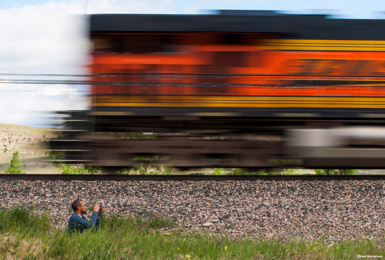 A railfan taking a photo of a diesel locomotive speeding by.