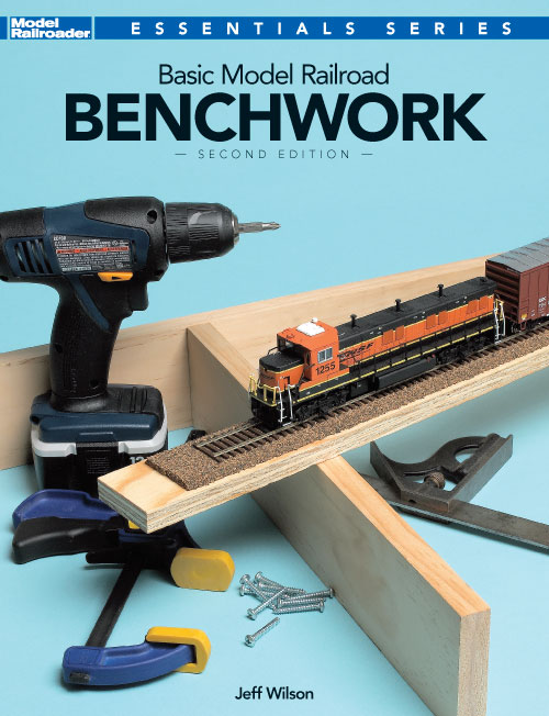 basic model railroad benchwork cover shows a variety of tools and wood by a HO scale diesel model