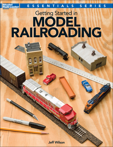 Getting started in model railroading cover showing benchwork with a variety of tools and a diesel train model